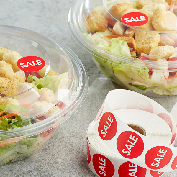 A salad in a bowl with a red Point Plus sale label next to a roll of Point Plus sale labels.