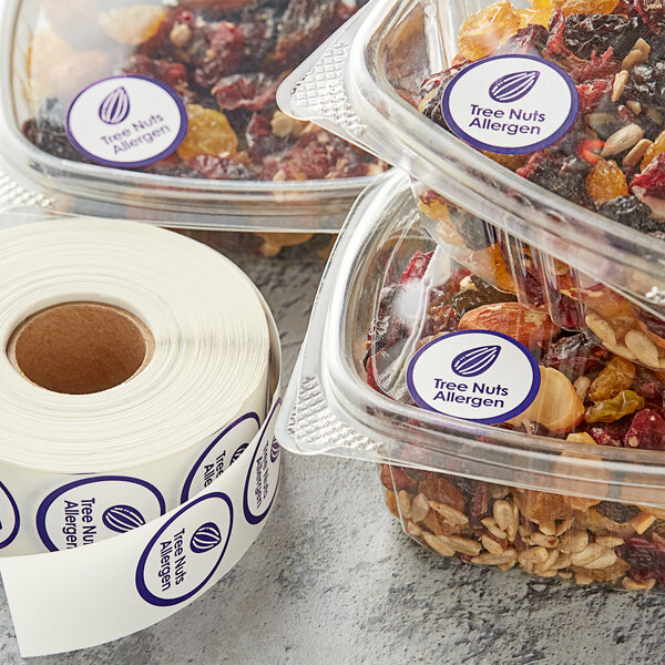 A roll of purple Point Plus tree nuts allergen labels on white paper next to a plastic container of nuts.