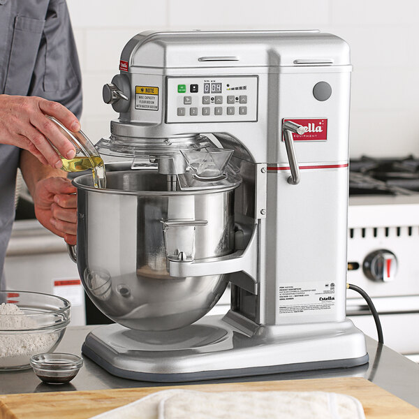 A man using a silver Estella countertop mixer to prepare a cake.