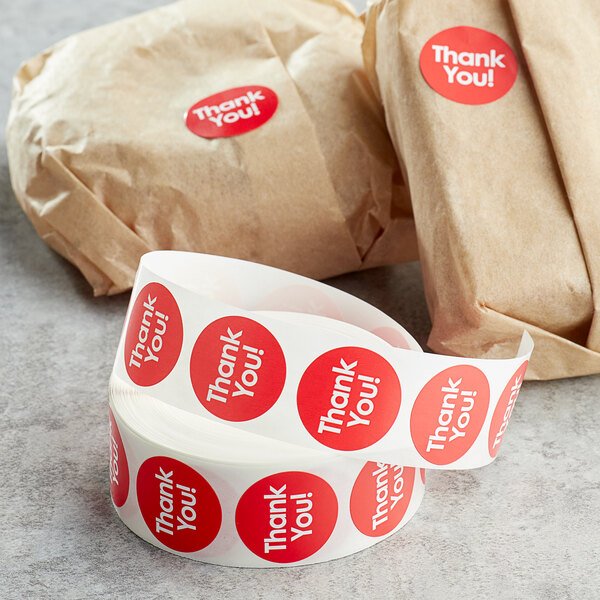 A roll of red Point Plus Thank You labels with white writing.