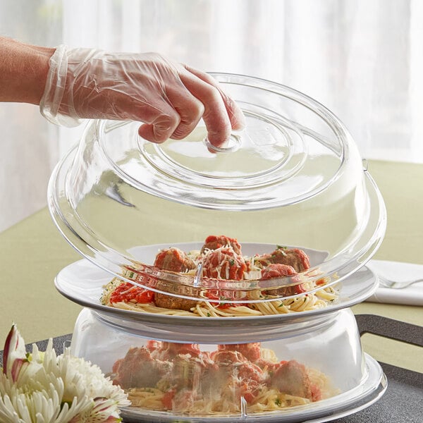 A person holding a Choice clear polycarbonate plate cover over food.