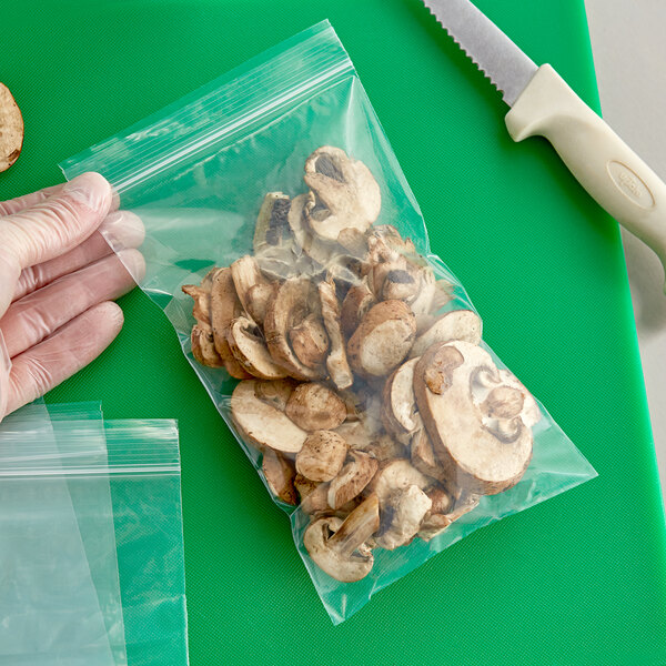 A hand using a Clear Line plastic bag to hold mushrooms.