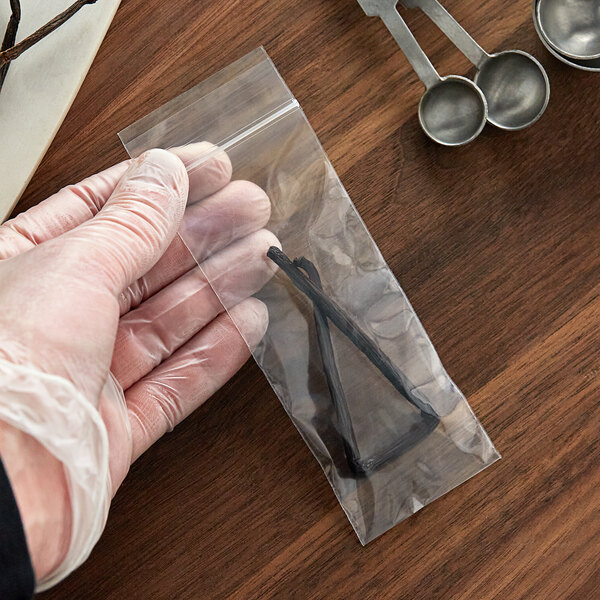 A hand using scissors to seal a Clear Line plastic food bag.