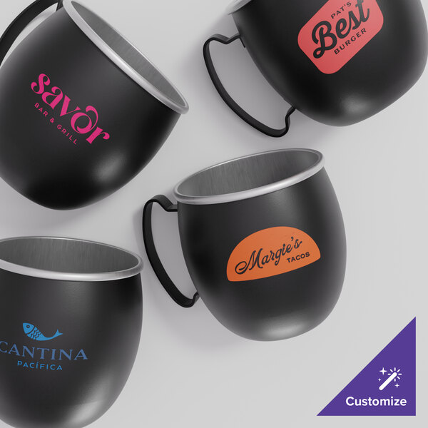 A set of four black Moscow mule mugs with different custom logos and text on each, featuring a metallic rim and handle.