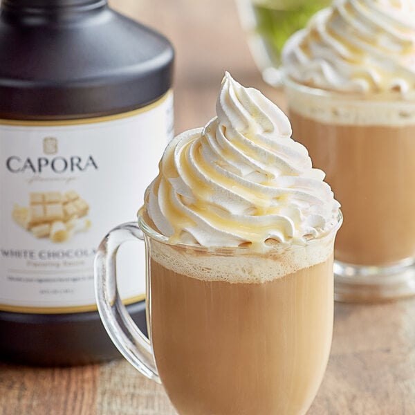 A glass mug of a drink with Capora White Chocolate Flavoring Sauce and whipped cream.