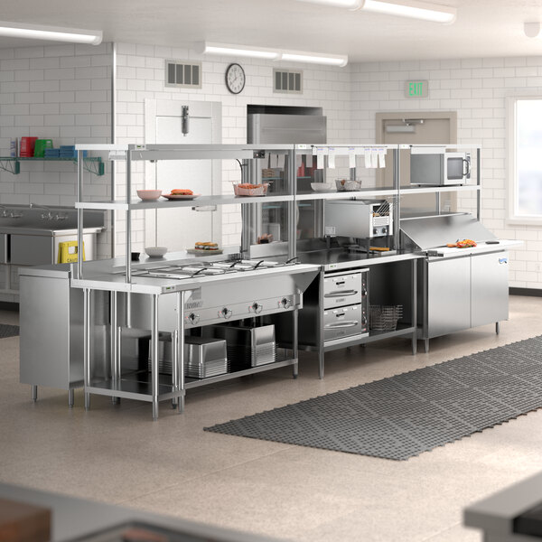 A Chef's Counter serving line with stainless steel appliances including a sandwich prep table, steam table, and work table.