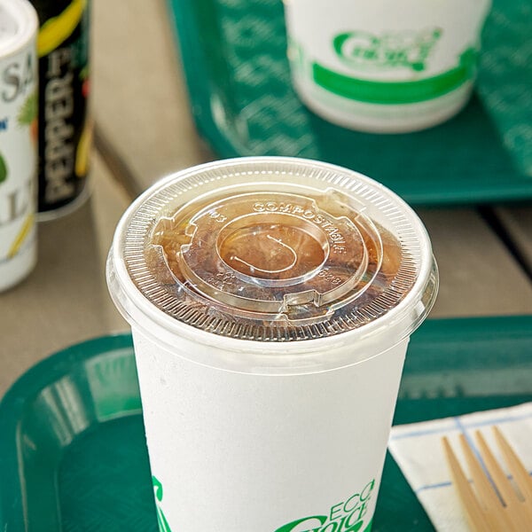 A white plastic cup with a translucent EcoChoice paper lid with a straw slot on a food court table.