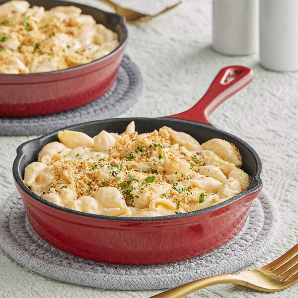 Two Valor cranberry apple enameled cast iron skillets with macaroni and cheese in them.