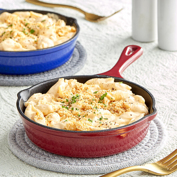 A red and blue Valor enameled cast iron skillet with macaroni and cheese in it.