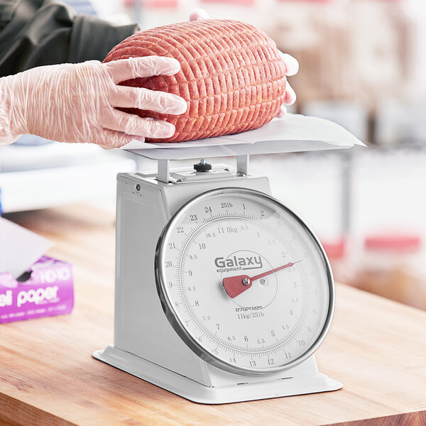 A person weighing meat on a Galaxy portion scale.