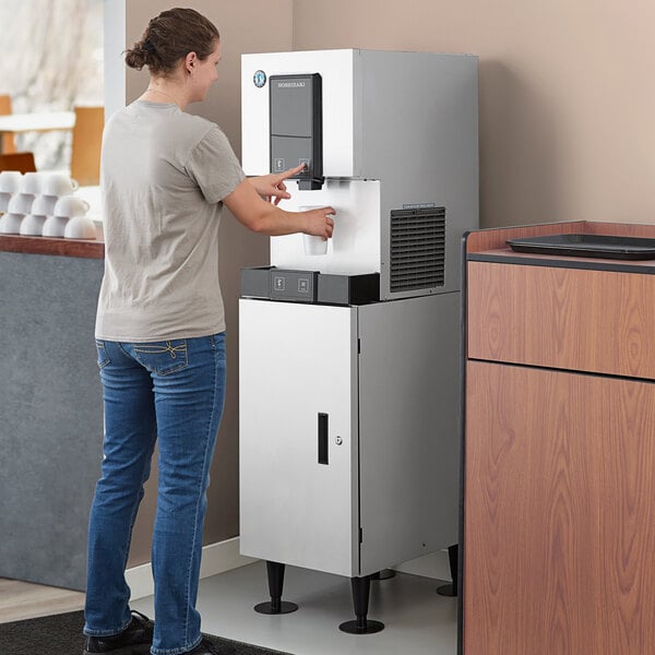 A woman using a Hoshizaki cubelet ice maker and water dispenser.