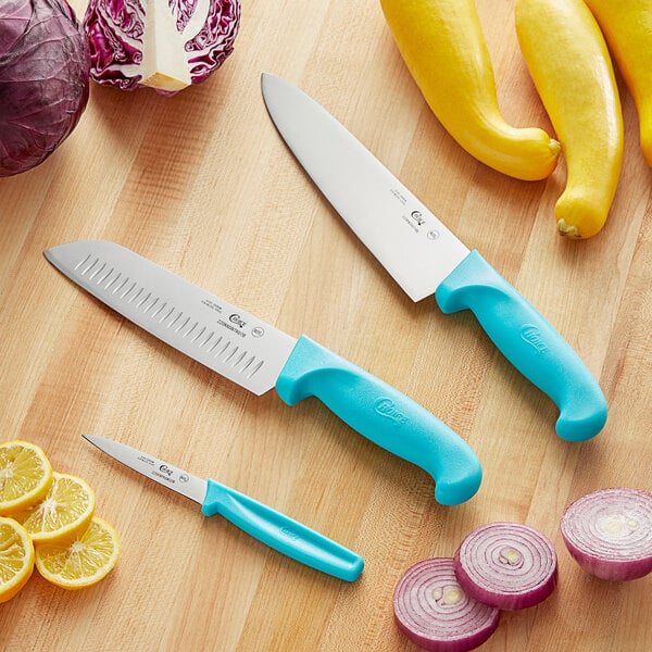 A Choice knife set with blue handles on a table with yellow squash and lemons.