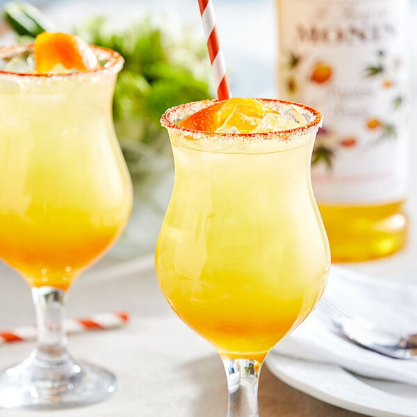 Two glasses of Monin passion fruit orange juice with a straw.