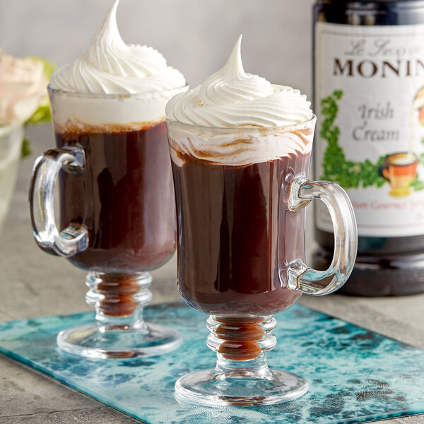 A glass mug of Monin Irish Cream flavored coffee with whipped cream on top.