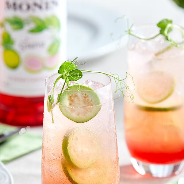 A glass of Monin guava-flavored drink with cucumber slices.