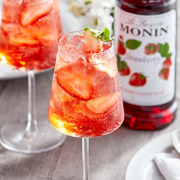 A glass of red liquid flavored with Monin Premium Strawberry Fruit Syrup.