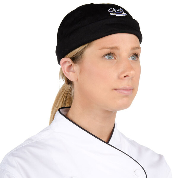 A woman wearing a black Chef Revival beanie with a white logo.