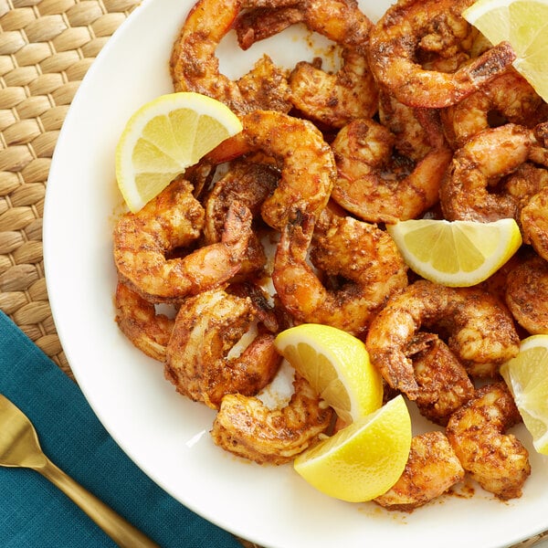 A plate of shrimp with Old Bay seasoning and lemon wedges.