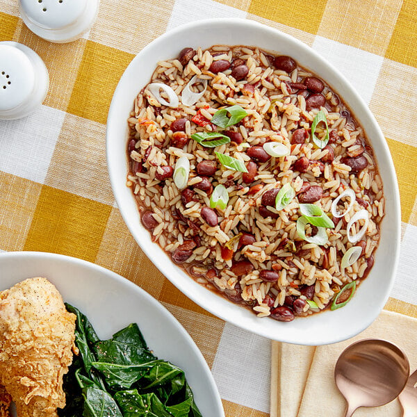 A bowl of Zatarain's red beans and rice with vegetables on a table.