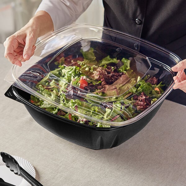 A person holding a Visions clear PET plastic lid on a salad container.