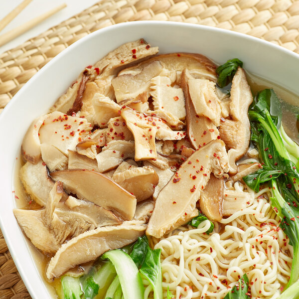 A bowl of soup with noodles, vegetables, and sliced Shiitake mushrooms.