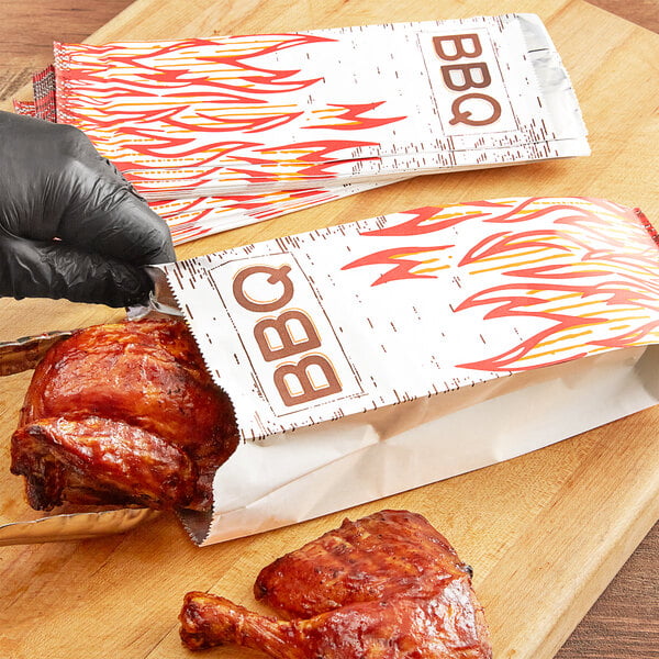 A person in gloves putting a piece of cooked meat in a Choice insulated foil BBQ bag.