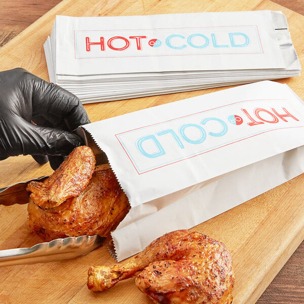 A person putting a chicken leg in a Choice insulated foil bag.