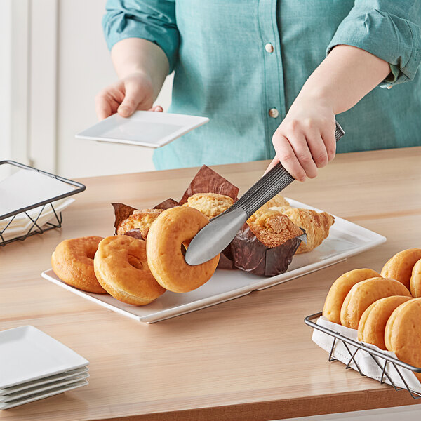 A person cutting doughnuts on an American Metalcraft white rectangular melamine tray.