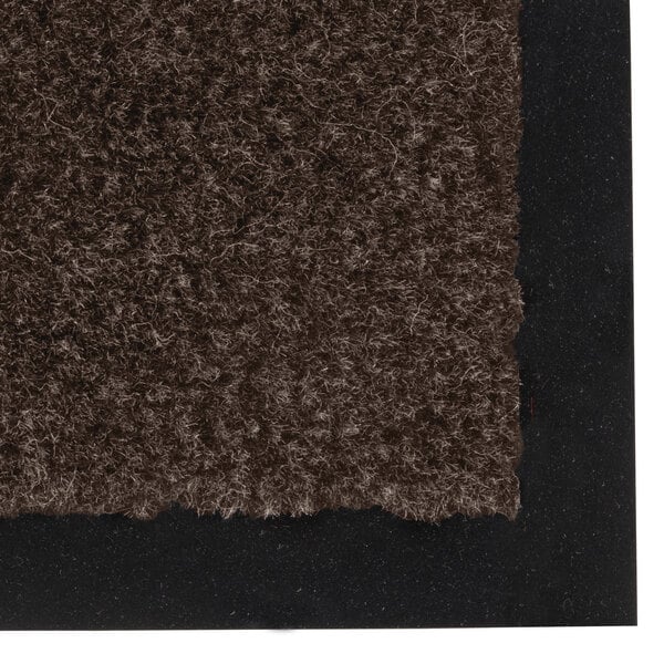 A dark brown carpet floor mat with black trim on top.