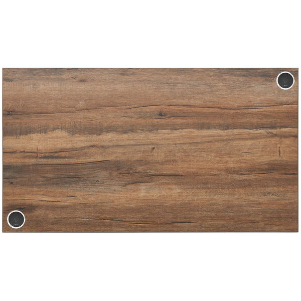 A wood grained rectangular table top with metal wireless chargers.