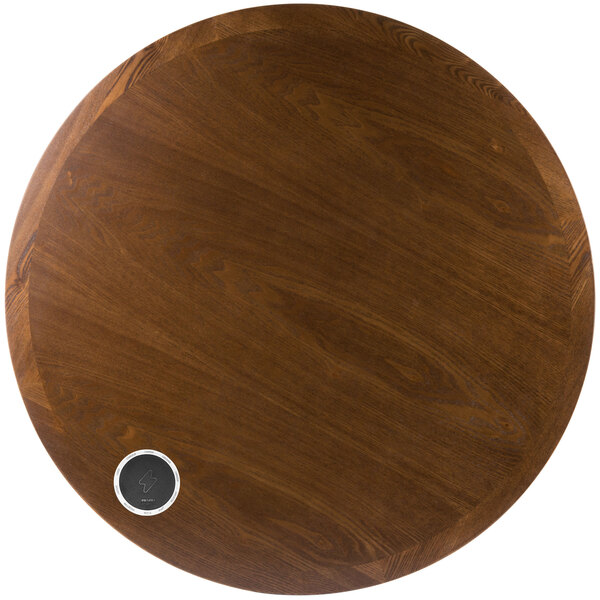 A round wooden table surface with a silver circle on it.