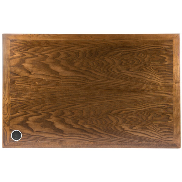 A BFM Seating rectangular wood table top with a round metal wireless charger.