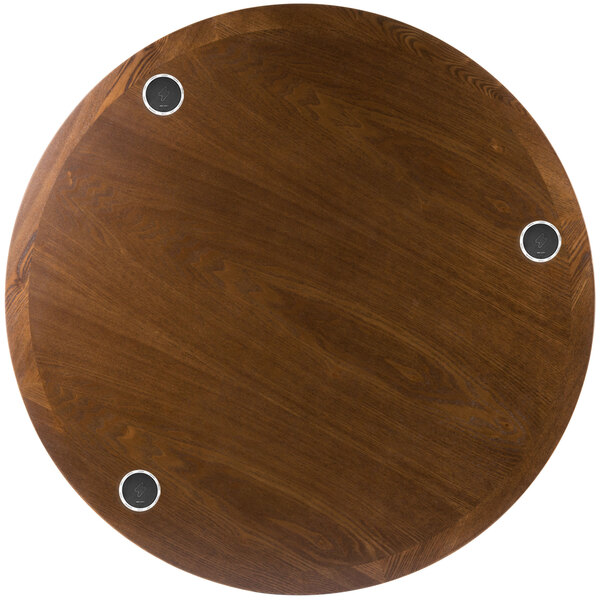 A BFM Seating round wooden table top with 3 wireless chargers.
