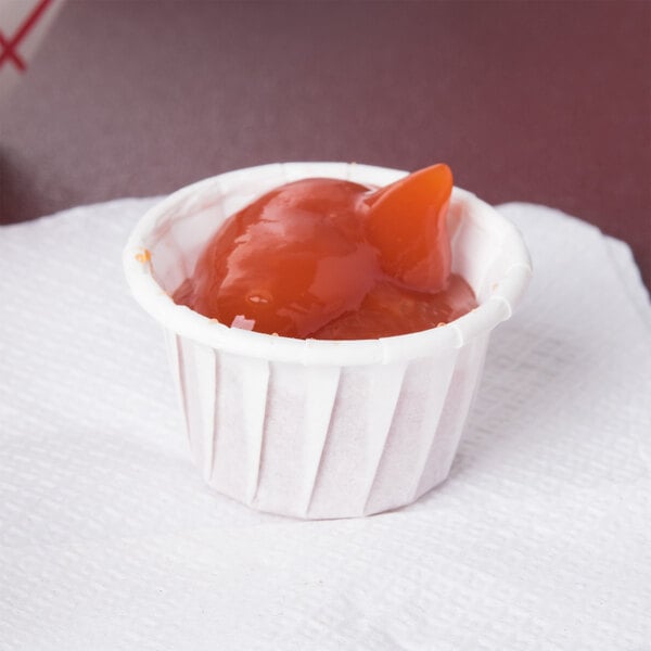 A Solo white paper souffle cup filled with food on a white surface.