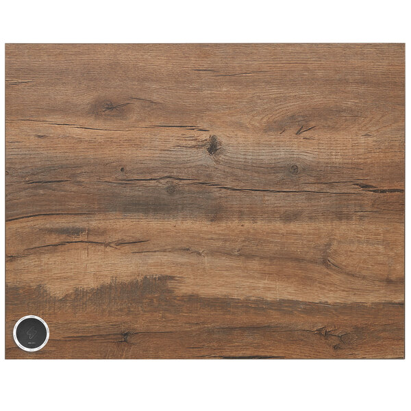 A dark brown knotty pine rectangular table top with a circular wireless charger in the middle.