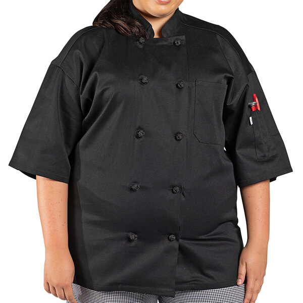 A woman wearing a black Uncommon Chef Antigua Pro Vent short sleeve chef coat with mesh back.