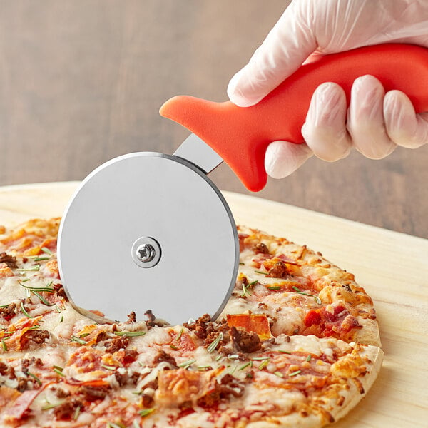 A gloved hand uses a Choice pizza cutter with a red handle to cut a pizza.