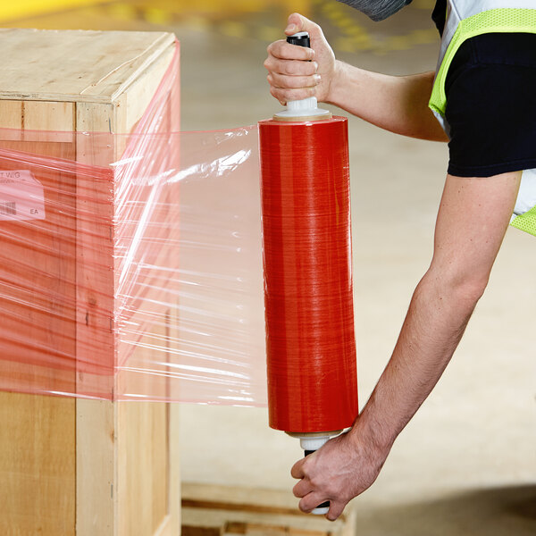 A man in a hard hat using a Lavex plastic stretch wrap dispenser with a black handle and grip to wrap pallets.