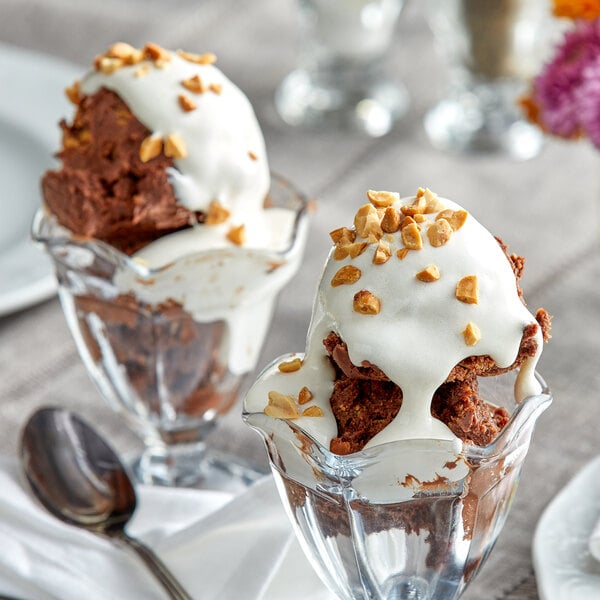 A chocolate ice cream sundae in a glass cup with J. Hungerford Smith marshmallow topping and nuts.