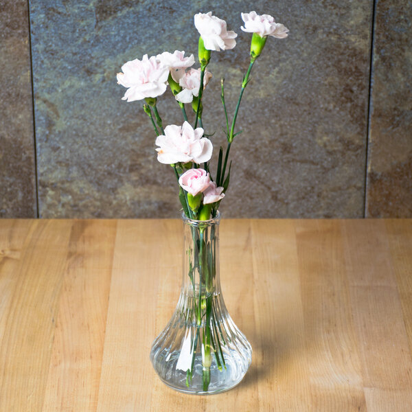 A clear polycarbonate Cambro bud vase with flowers on a table.
