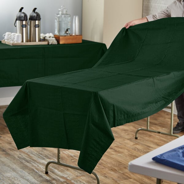 A man using a Hoffmaster green paper table cover on a table.