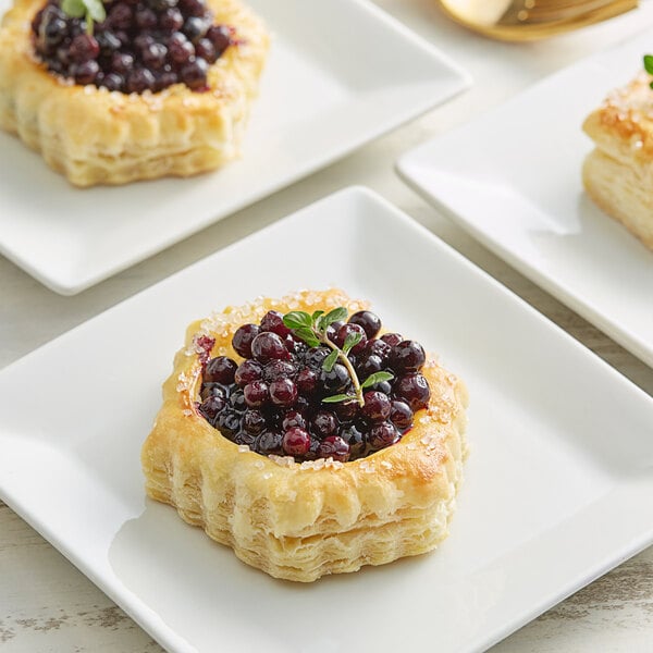 A white pastry with blueberries on top on a white plate.