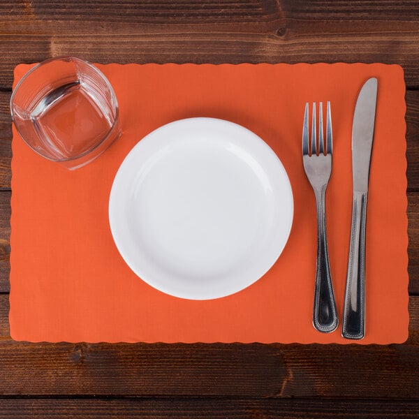 A white plate with a glass and silverware on a Bittersweet Orange Hoffmaster paper placemat.