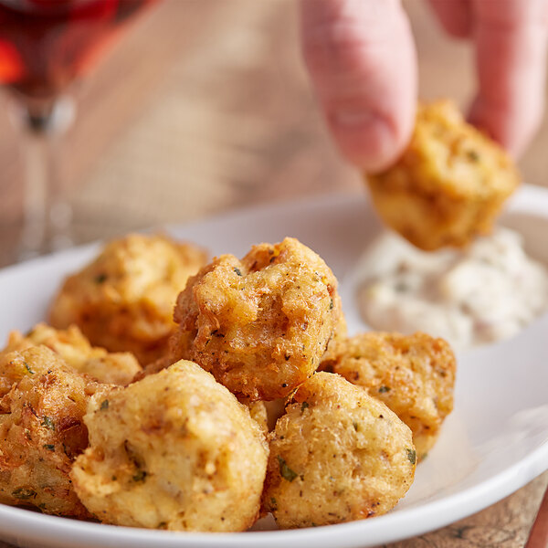 A person holding a plate of Handy pub style crab cakes with a glass of wine.