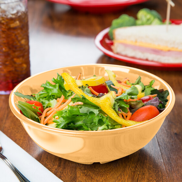 A bowl of salad with vegetables in a yellow Diamond Mardi Gras melamine bowl.