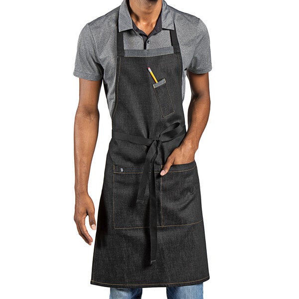 A man wearing a black Uncommon Chef bib apron with pockets.