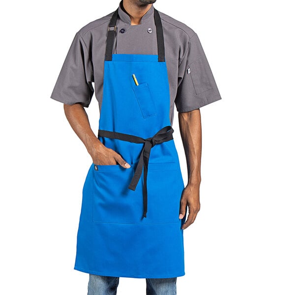 A man wearing a blue Uncommon Chef bib apron with black webbing.
