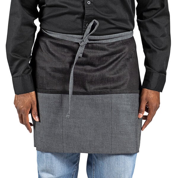 A person wearing a Uncommon Chef black denim waist apron with black webbing.