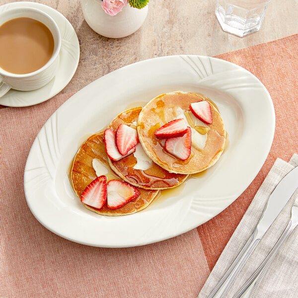 A plate of Acopa ivory stoneware with pancakes, strawberries, and syrup.