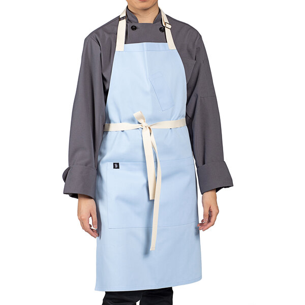 A man wearing a sky blue Uncommon Chef apron with natural webbing.
